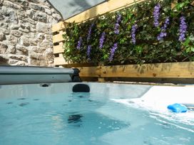 A hot tub in an outdoor area with a stone wall and plants at Wonderland in Tweedmouth, Berwick-Upon-Tweed