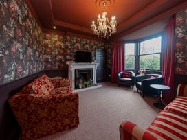 A living room with a sofa, armchairs, a television, and a fireplace at Wonderland in Tweedmouth, Berwick-Upon-Tweed