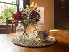 A table with flowers in a vase and a cup at Wonderland in Tweedmouth, Berwick-Upon-Tweed