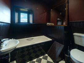 A bathroom with a bathtub, sink, toilet, and mirror at Wonderland in Tweedmouth, Berwick-Upon-Tweed