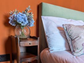 A bedside table with a vase of flowers next to a bed at Wonderland in Tweedmouth, Berwick-Upon-Tweed