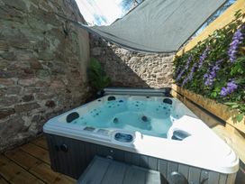 A hot tub surrounded by stone walls and plants at Wonderland in Tweedmouth, Berwick-Upon-Tweed