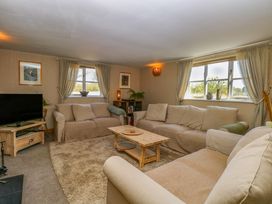 A living room with beige sofas a wooden coffee table and a television at Wayford Mill in Wayford