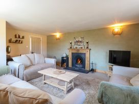 A living room with sofas coffee table fireplace and television at Wayford Mill in Wayford