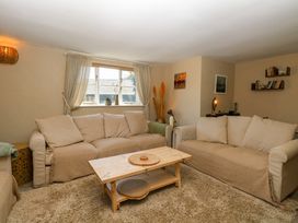 A living room with two beige sofas a wooden coffee table and window with curtains at Wayford Mill in Wayford