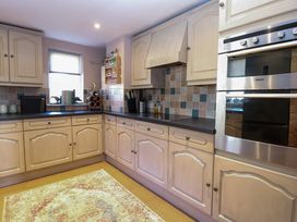 A kitchen with wooden cabinets a built in oven a wine rack and tiled backsplash at Wayford Mill in Wayford