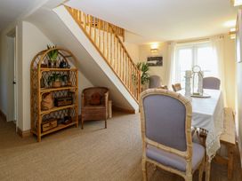 A dining area with a table and chairs next to a staircase and a shelving unit at Wayford Mill in Wayford
