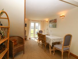 A dining room with a table covered by a white cloth and chairs by a glass door with a view outside at Wayford Mill in Wayford