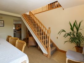 A room with wooden staircase carpeted steps wicker chairs a table with white cloth a plant and an upholstered chair at Wayford Mill in Wayford