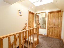 A landing with wooden banister two wooden doors a large mirror and a framed picture at Wayford Mill in Wayford