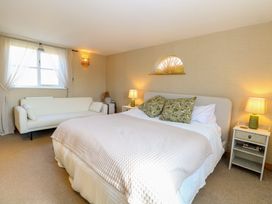 A bedroom with a bed sofa side tables with lamps and a window at Wayford Mill in Wayford