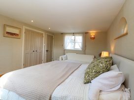 A bedroom with a bed a white sofa and beige doors at Wayford Mill in Wayford