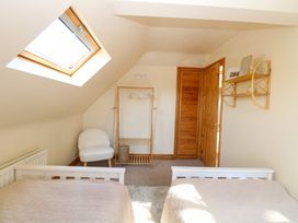 A bedroom with two beds under a skylight and a white chair with a wooden clothes rack at Wayford Mill in Wayford
