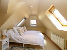 A bedroom with a double bed pillows bedside table lamp and three skylight windows at Wayford Mill in Wayford
