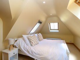 A bedroom with a white bed and patterned pillows under sloped ceilings with two small windows at Wayford Mill in Wayford
