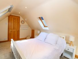 A bedroom with a white bed and side tables with lamps under a skylight at Wayford Mill in Wayford