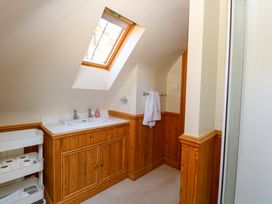 A bathroom with a wooden vanity cabinet under a sloped ceiling window and a white towel hanging on a wall rail at Wayford Mill in Wayford