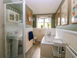 A bathroom with a shower cubicle, bathtub, toilet, sink, and wall decorations at Wayford Mill in Wayford