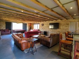 A wooden interior lounge with sofas a pool table a wall mounted TV and bar stools at Wayford Mill in Wayford