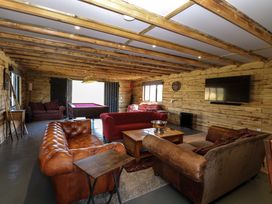 A recreational room with wooden walls and ceiling beams featuring leather and fabric sofas a pool table a dartboard and a wall-mounted television at Wayford Mill in Wayford