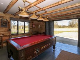 A room with a red pool table wood paneled walls and a large window and open door at Wayford Mill in Wayford
