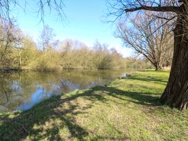 A river with trees along the bank and grassy area at Wayford Mill in Wayford