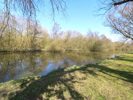 A river bordered by grassy banks and leafless trees under a clear sky at Wayford Mill in Wayford