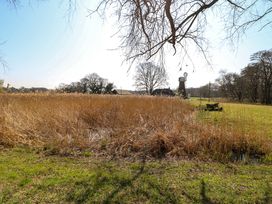 A field with tall dry grass and a windmill with buildings in the background at Wayford Mill in Wayford