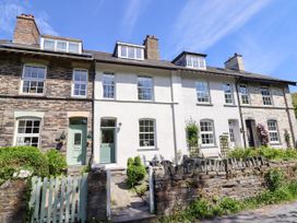 A row of stone and white townhouses with green doors and small front gardens at Glan yr Afon in Abergynolwyn near Tywyn