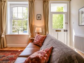 A living room with a leather sofa and patterned cushions next to a window and door at Glan yr Afon in Abergynolwyn near Tywyn