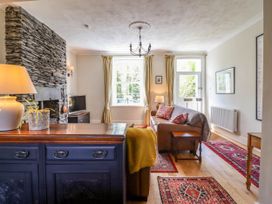A living room with a stone fireplace sofas a wooden sideboard and a television at Glan yr Afon in Abergynolwyn near Tywyn