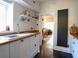 A kitchen with a sink wooden countertops white cabinets and a doorway leading to a dining area at Glan yr Afon in Abergynolwyn near Tywyn