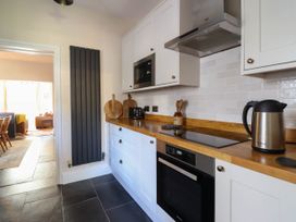 A kitchen with a wooden countertop electric stove oven microwave kettle and cutting boards at Glan yr Afon in Abergynolwyn near Tywyn