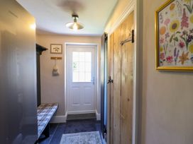 A hallway with a wooden door a bench a white door and a framed floral picture at Glan yr Afon in Abergynolwyn near Tywyn