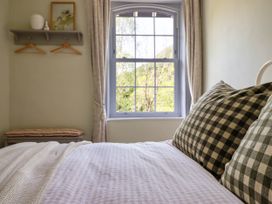 A bedroom with a window and checkered pillows on the bed at Glan yr Afon in Abergynolwyn near Tywyn