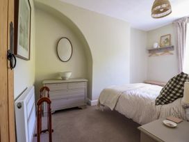 A bedroom with a bed bedside table chest of drawers and a hanging rack at Glan yr Afon in Abergynolwyn near Tywyn