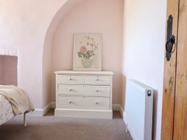 A bedroom corner with a white chest of drawers and a floral painting above at Glan yr Afon in Abergynolwyn near Tywyn