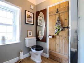 A bathroom with a toilet a wooden door a towel hanging a window and framed pictures at Glan yr Afon in Abergynolwyn near Tywyn
