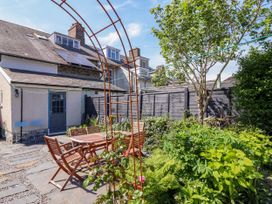 A garden with wooden table and chairs next to a house with solar panels at Glan yr Afon in Abergynolwyn near Tywyn