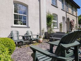 A patio with outdoor chairs and a bench against a white house wall at Glan yr Afon in Abergynolwyn near Tywyn