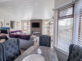 A living room with a television and dining table at JacMar Lodge, 14 Applethwaite, Limefitt Park near Windermere