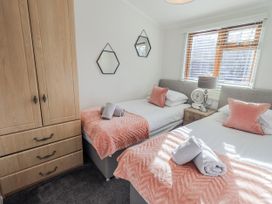 A bedroom with twin beds and a wardrobe at JacMar Lodge, 14 Applethwaite, Limefitt Park near Windermere