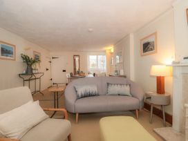 A living room with sofas a lamp a side table a dining table and framed pictures on the wall at Lavender Cottage in Lyme Regis