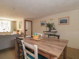 A dining area with a wooden table and mixed chairs next to a living room with a sofa and window at Lavender Cottage in Lyme Regis