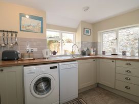 A kitchen with washing machine dishwasher sink countertop and utensils at Lavender Cottage in Lyme Regis