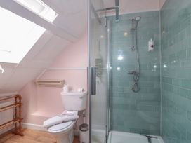 A bathroom with a toilet and a glass shower with green tiles at Lavender Cottage in Lyme Regis