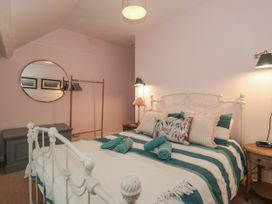 A bedroom with a striped bed and pillows and a round mirror on the wall at Lavender Cottage in Lyme Regis
