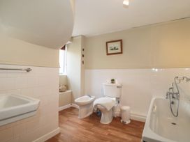 A bathroom with a sink toilet bidet bathtub and wooden floor at Lavender Cottage in Lyme Regis