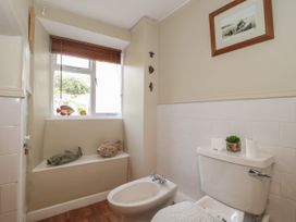 A bathroom with a bidet, toilet, window with fish decorations, and a framed picture on the wall at Lavender Cottage in Lyme Regis