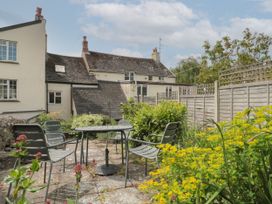 An outdoor patio with metal chairs and a table surrounded by plants and flowers at Lavender Cottage in Lyme Regis